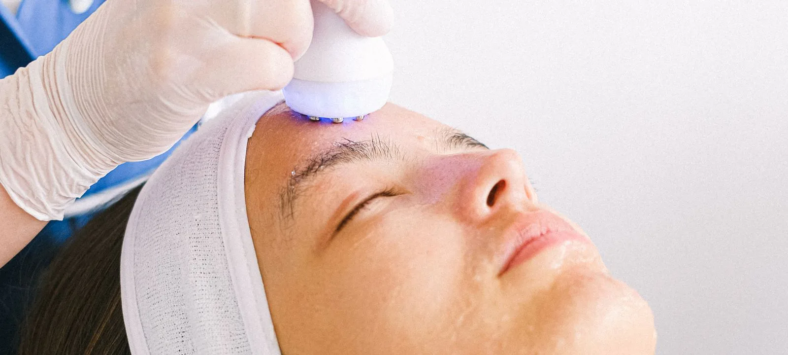 Derma terapi cihazını danışanın yanağına uygulayan uzman